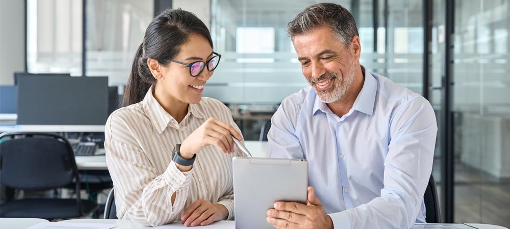 Mann und Frau besprechen etwas auf einem Tablet im B&uuml;ro